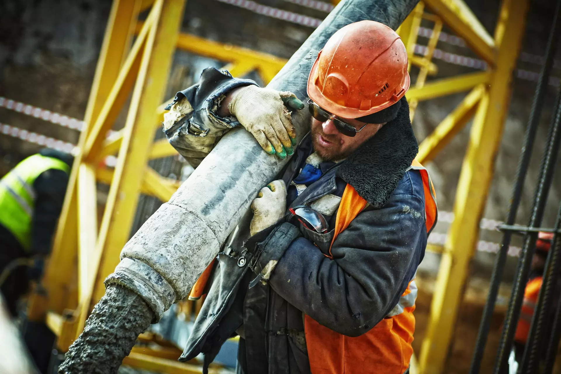 Ein Mann steht auf einer Baustelle, aus einem Schlauch fließt Beton